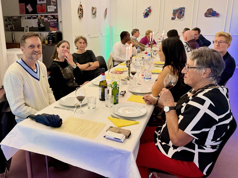 Gäste an der langen, mit Kerzen gedeckten Tafel